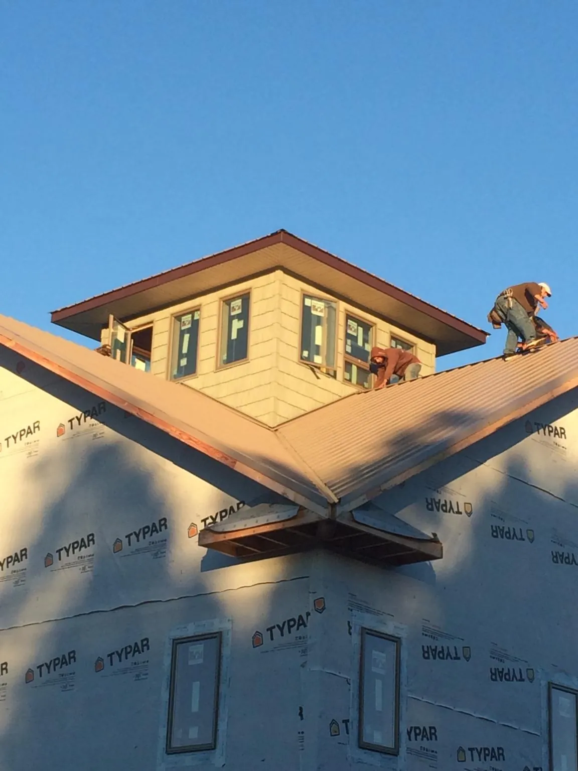 Roofers working around a rooftop cupola on a new metal roof at sunset — Roof Waterproofing in Sullivan by Roofing Brothers
